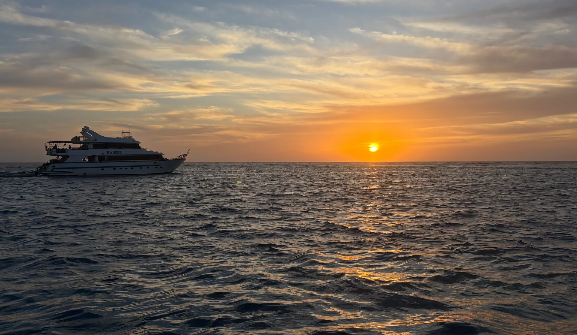 The yacht silhouetted against a wide Red Sea sunset on the final evening